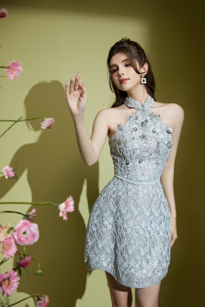 Chic portrait of a woman in a floral dress posing stylishly against a yellow background.